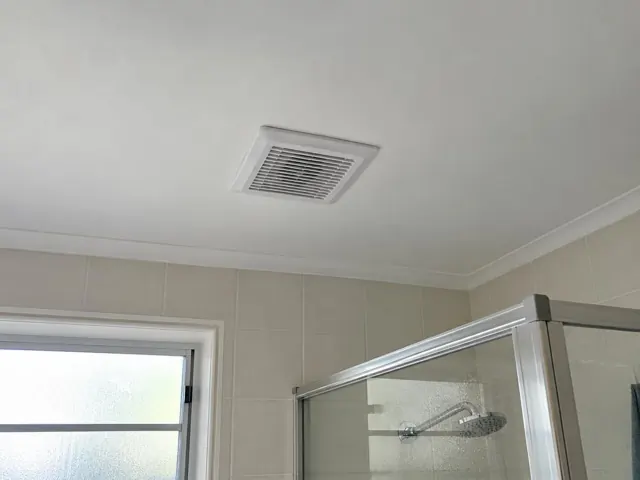 Ceiling exhaust fan above tiled bathroom shower with glass screen in Narrabeen